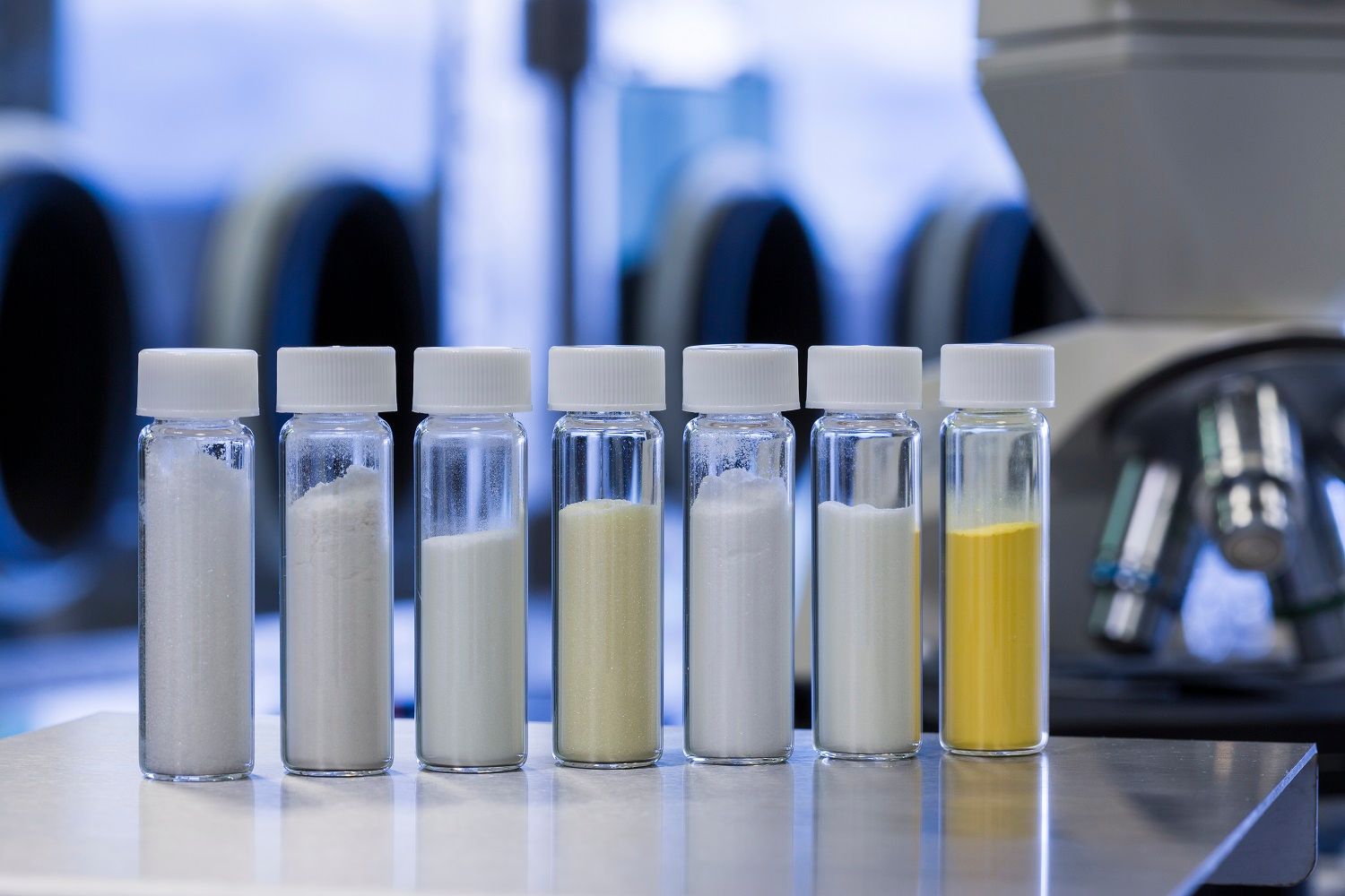 Sieben Gläser mit Materialien, die in einer Reihe stehen