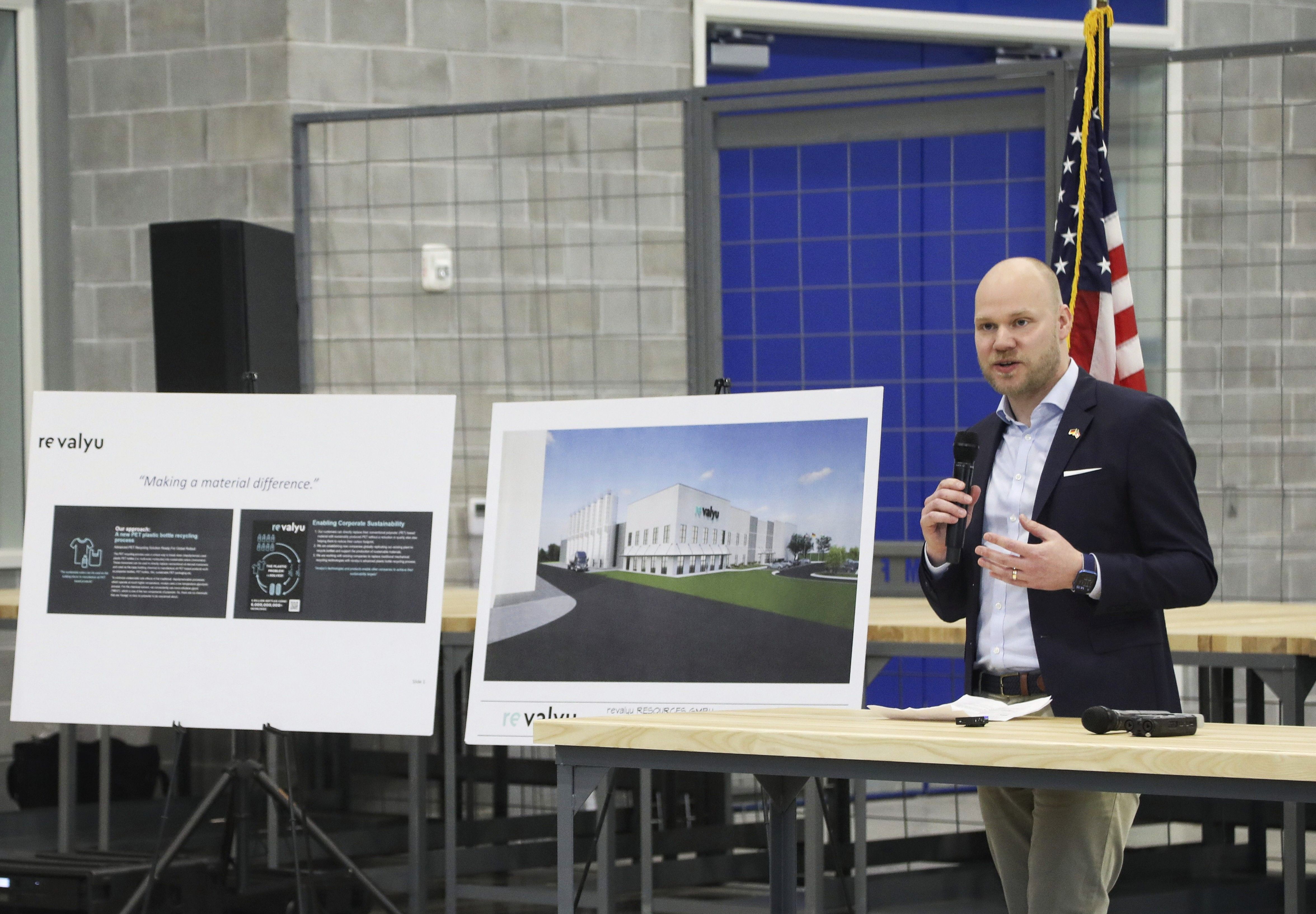 Jan van Kisfeld, Managing Director of revalyu, speaking with a microphone next to two posters 