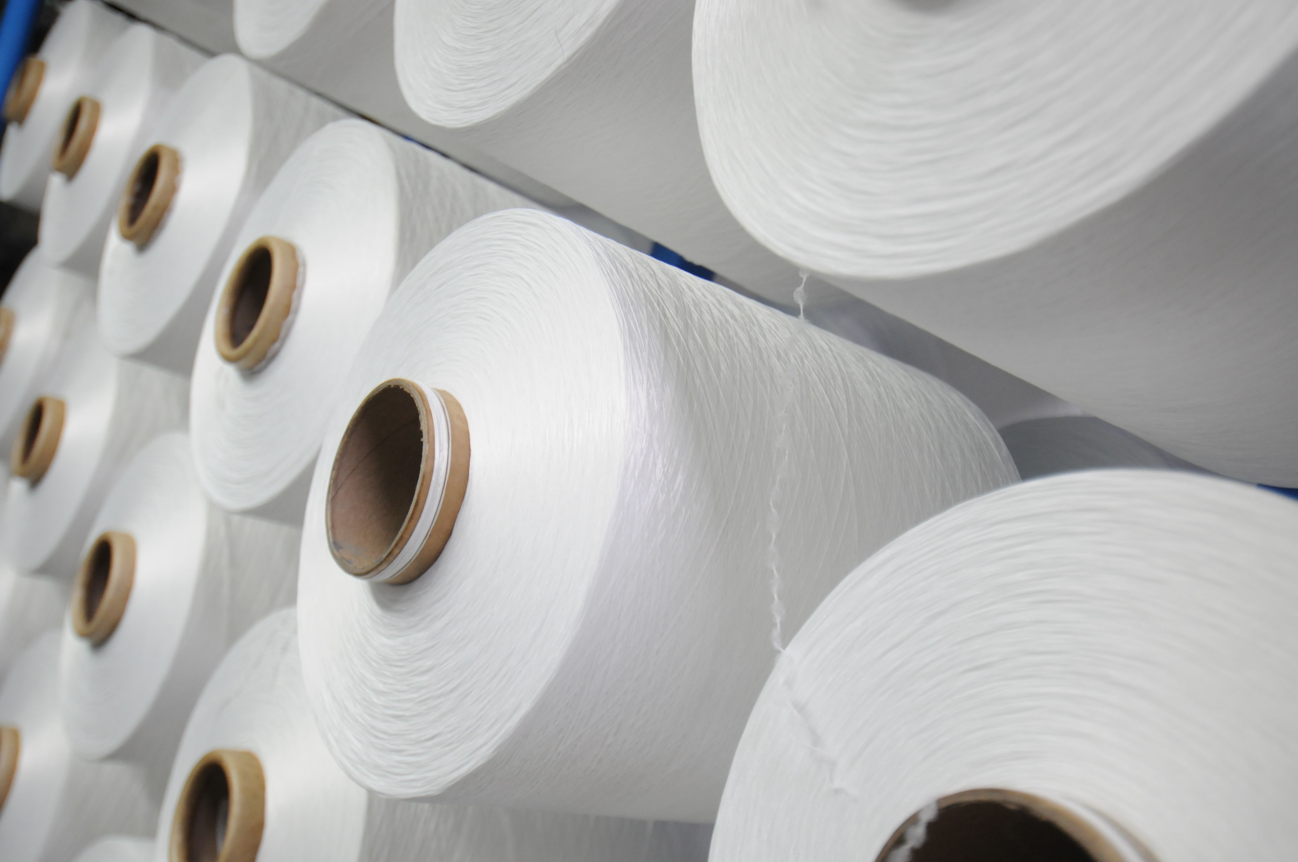 Multiple white yarn rolls laying on one another 